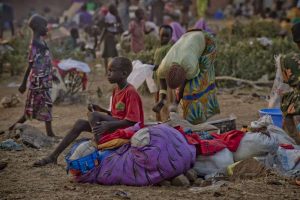 A young South Sudanese boy sits on a bundle of clothes at Dzaipi Reception Centre in northern Uganda. © UNHCR/F. Noy