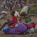 A young South Sudanese boy sits on a bundle of clothes at Dzaipi Reception Centre in northern Uganda. © UNHCR/F. Noy